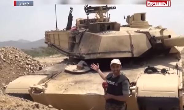 An Al Masirah reporter and Houthis stand next to a captured Saudi M1 Abrams tank 1.jpg